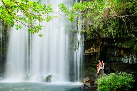 Two woman relaxing next to a waterfall.  Llanos de Cortes Waterfall in Bagaces, Guanacaste